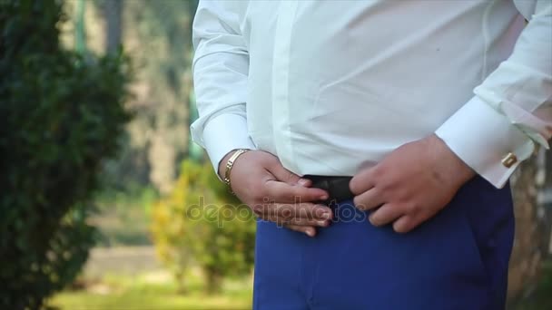 Man corrigeert riem close-up bruidegom wit shirt — Stockvideo