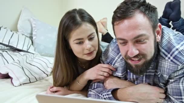 Счастливая пара с ноутбуком, лежащим на кровати дома — стоковое видео
