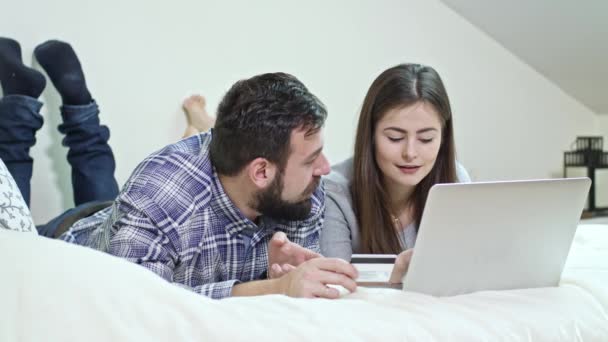 Couple heureux en utilisant un ordinateur portable allongé sur un lit à la maison — Video