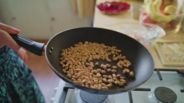 Mujer asando cacahuetes en una sartén — Vídeos de Stock