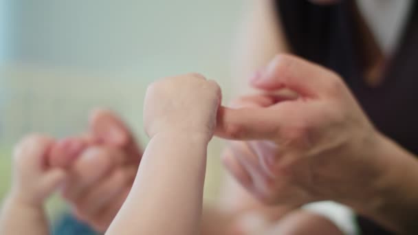 Babys λίγο χέρι είναι κρατώντας το δάχτυλό μητέρες — Αρχείο Βίντεο