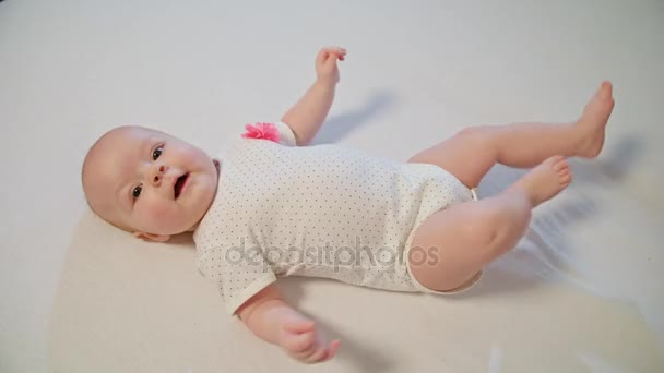Kleine nieuwsgierige Baby is leggen op een witte deken en rondkijken — Stockvideo