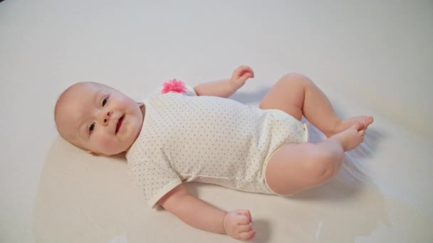 Petit bébé curieux pose sur une couverture blanche et regarde autour de lui — Video