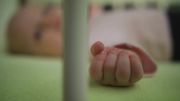 Baby liegt auf dem Rücken in seiner Krippe Bewegung Nahaufnahme Hand — Stockvideo