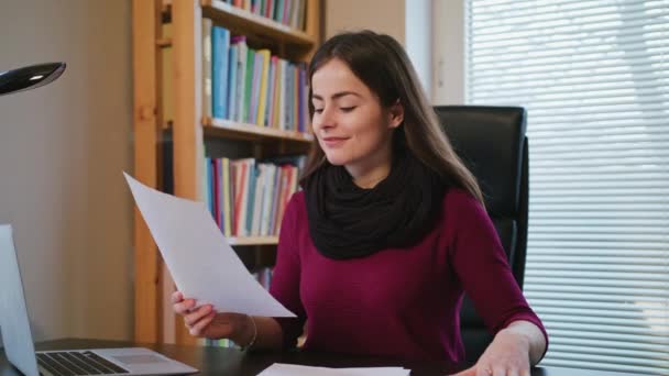 Fröhliche junge Frau schaut auf Dokumente. — Stockvideo