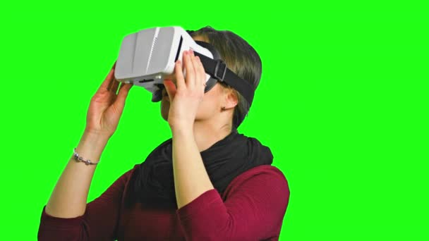 Mujer girando la cabeza con un auricular VR encendido . — Vídeos de Stock