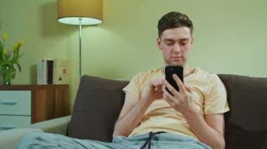 Adam kanepede oturan ve istimal hareket eden telefon