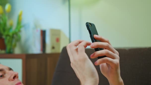 L'homme pose sur le canapé et utilise son téléphone portable — Video