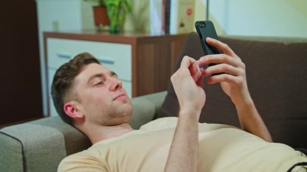 Ο άνθρωπος για τον καθορισμό στον καναπέ και χρήση κινητού τηλεφώνου — Αρχείο Βίντεο