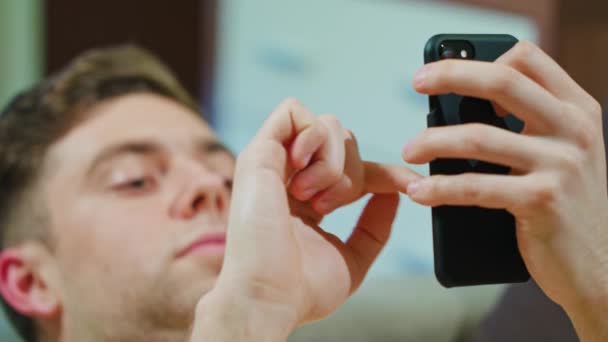 Muž položil na pohovku a pomocí mobilního telefonu — Stock video