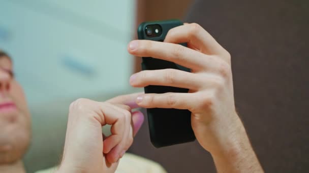 Man lägger på soffan och med mobiltelefon — Stockvideo