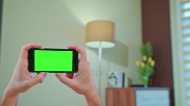 Erkek eller yeşil ekranlı bir telefonu tutuyor.
