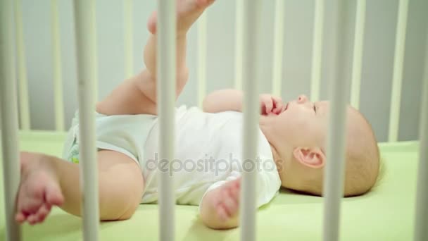 Dziecko leży w łóżeczku w Strona główna jedzenie jej palce — Wideo stockowe