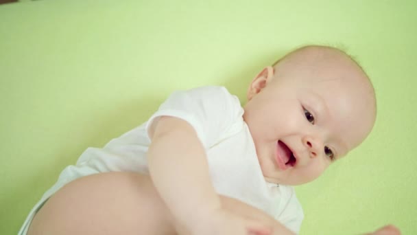 Bebé acostado en una cuna en casa comiendo sus dedos de los pies — Vídeos de Stock