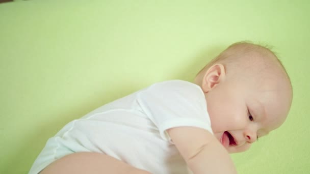 Μωρό ξαπλωμένη σε ένα παχνί στο σπίτι τρώει τα δάχτυλα — Αρχείο Βίντεο