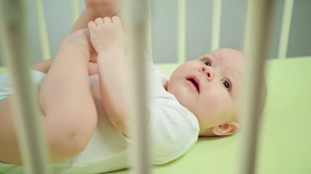 Ребенок, лежащий дома в детской кроватке и плачущий — стоковое видео