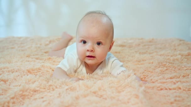 Малыш лежит на животе на уютном ковре — стоковое видео