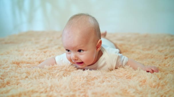 Baby liegt auf dem Bauch auf einem kuscheligen Teppich — Stockvideo