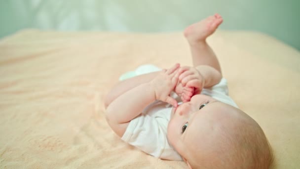 Baby Lying in Bed Home eten zijn voet — Stockvideo