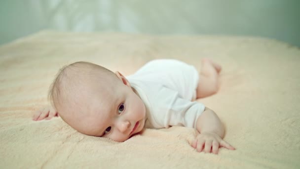 Feküdt a gyomor egy puha ágynemű mosolygós baba — Stock videók