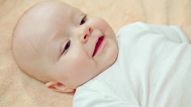 Bebé acostado en una ropa de cama suave sonriendo — Vídeo de stock