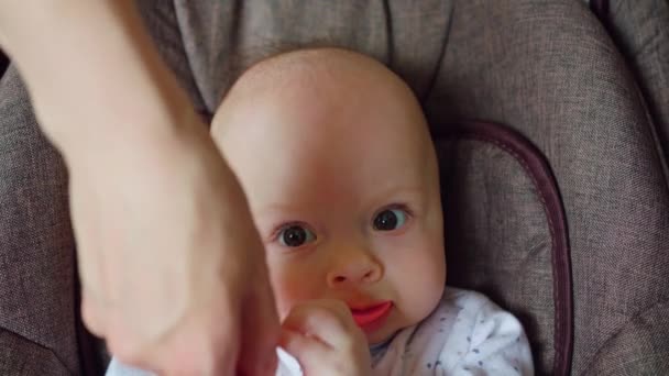 Cute Baby Lying in Pram Eating a Red Spoon — Stock Video