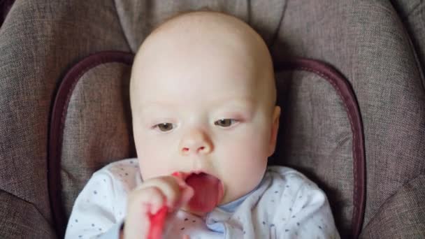 Cute Baby Lying in Pram Eating a Red Spoon — Stock Video