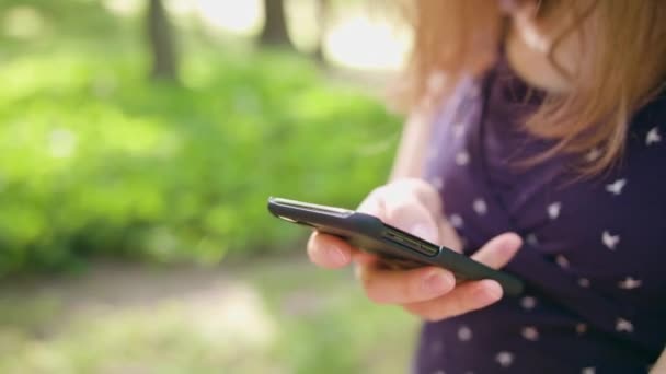 Vrouw met behulp van een telefoon in het Park — Stockvideo