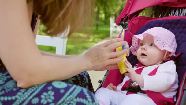 Frau mit Kinderwagen sitzt auf Bank im Park — Stockvideo