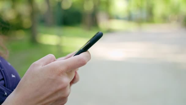 Жінка використовує телефон у парку — стокове відео