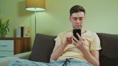 Adam kanepede oturan ve istimal hareket eden telefon