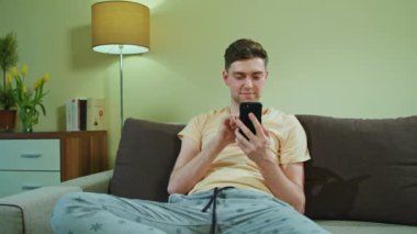 Adam kanepede oturan ve istimal hareket eden telefon