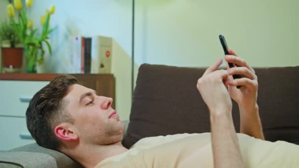 Ο άνθρωπος για τον καθορισμό στον καναπέ και χρήση κινητού τηλεφώνου — Αρχείο Βίντεο