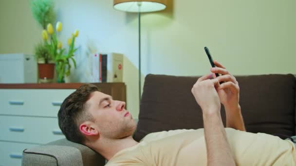 L'homme pose sur le canapé et utilise son téléphone portable — Video