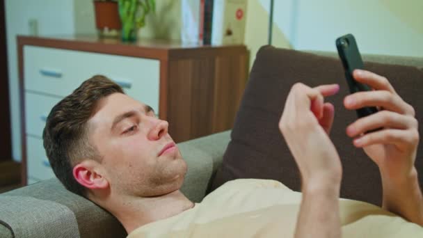 Man Laying on the Sofa and using Mobile Phone — Stok Video