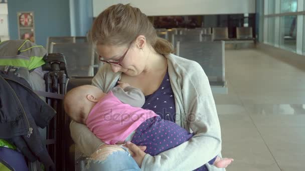 Uma mulher amamentando seu filho no aeroporto — Vídeo de Stock