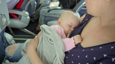 Bir kadın emzirme çocuğunu bir uçakta