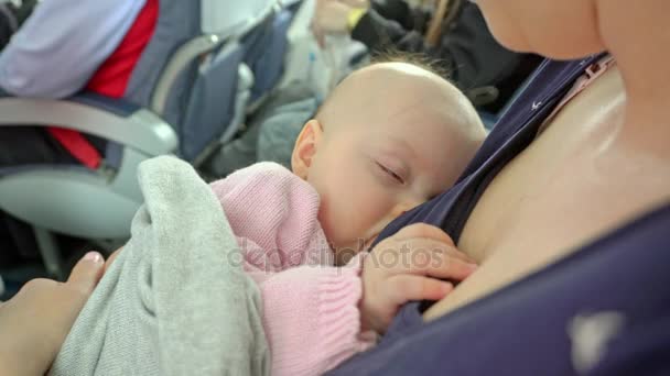 Eine Frau, die ihr Kind im Flugzeug stillt — Stockvideo