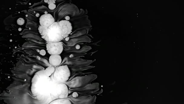 Islak siyah ekran arka plan üzerinde beyaz mürekkep damlaları — Stok video