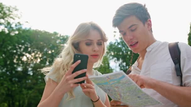 Um casal jovem usando um telefone celular ao ar livre — Vídeo de Stock