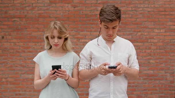 Um jovem casal usando telefones celulares ao ar livre — Vídeo de Stock