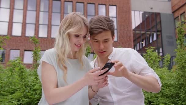 Un jeune couple utilisant un téléphone portable à l'extérieur — Video