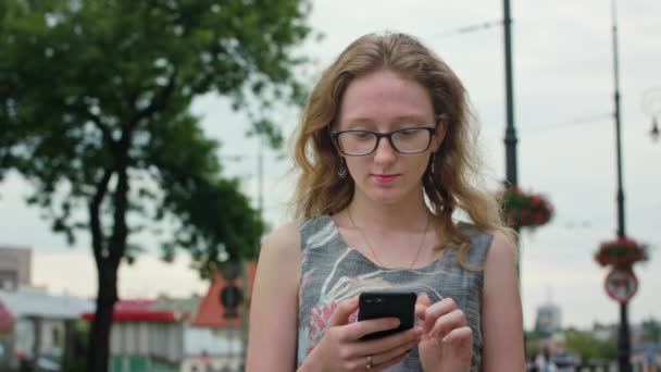 En vacker rödhårig med en mobiltelefon-utomhus — Stockvideo