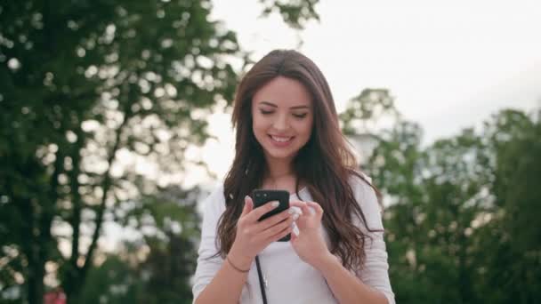 Una hermosa morena usando un teléfono móvil al aire libre — Vídeos de Stock