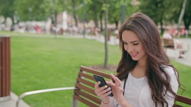 Een prachtige Brunette met behulp van een mobiele telefoon in de buitenlucht — Stockvideo