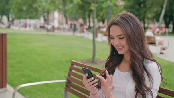 Una hermosa morena usando un teléfono móvil al aire libre — Vídeos de Stock