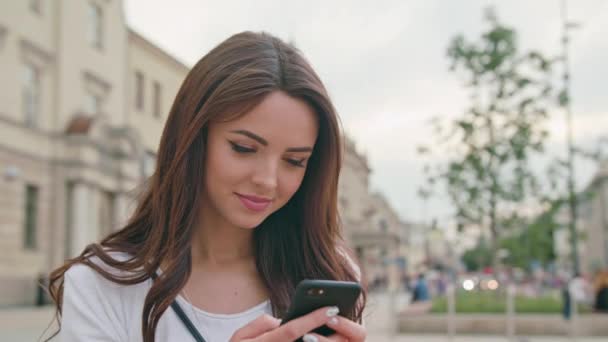 Egy gyönyörű barna használatával egy mobil telefon a szabadban — Stock videók