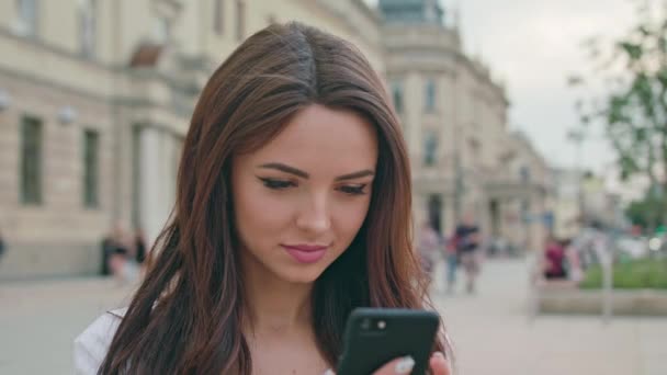 Eine schöne Brünette mit einem Mobiltelefon im Freien — Stockvideo