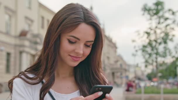 Een prachtige Brunette met behulp van een mobiele telefoon in de buitenlucht — Stockvideo