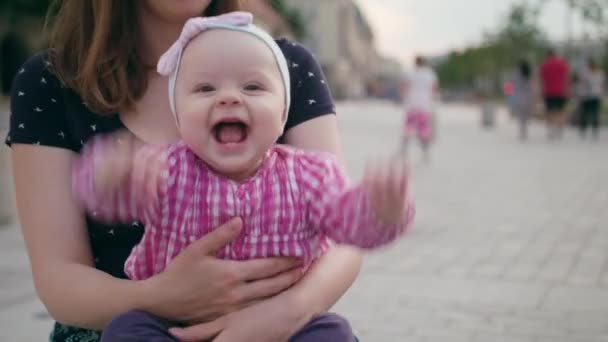 Una hermosa morena sosteniendo a un bebé sobre sus rodillas — Vídeos de Stock